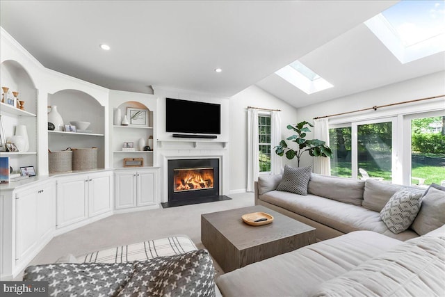 living room with a skylight, light colored carpet, a fireplace with flush hearth, vaulted ceiling, and built in features