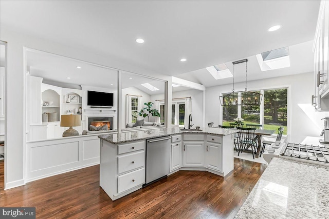kitchen featuring dishwasher, a skylight, dark wood-type flooring, a sink, and white cabinetry