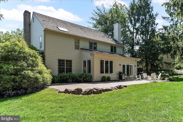 back of house featuring a chimney, a patio area, and a yard