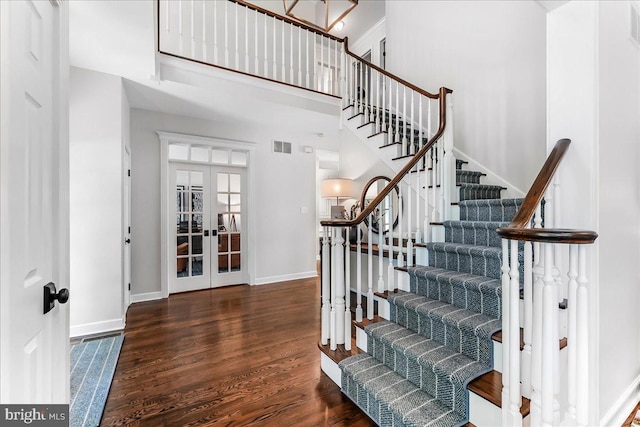 stairs with wood finished floors, french doors, baseboards, and a towering ceiling
