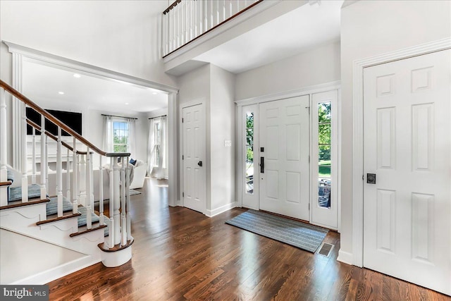 foyer entrance featuring stairway, wood finished floors, a towering ceiling, and baseboards