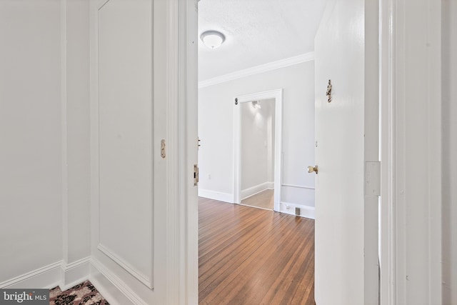 hall featuring crown molding, wood finished floors, and baseboards