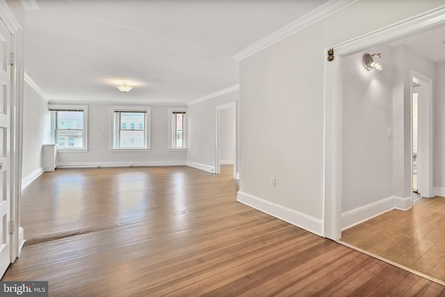 unfurnished living room featuring wood-type flooring, baseboards, and crown molding