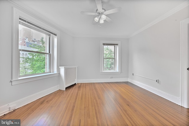 spare room with baseboards, wood-type flooring, ceiling fan, and crown molding