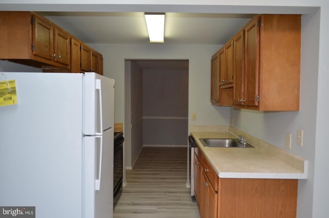 18050 Chalet Dr Unit 14-303, Germantown, MD 20874 - kitchen with freestanding refrigerator, a sink, light countertops, light wood-style flooring, and brown cabinetry