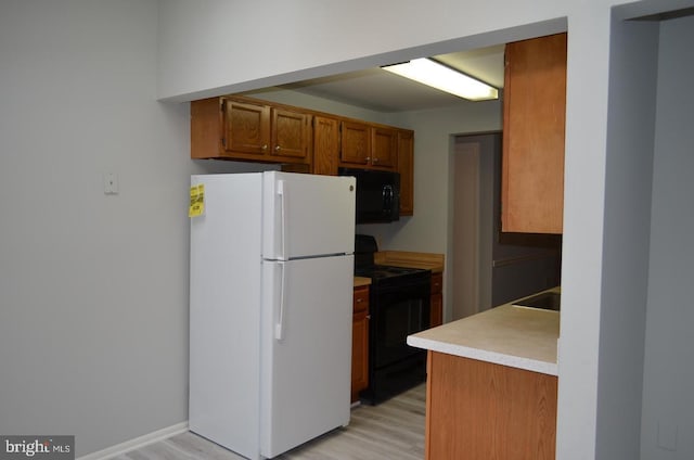 18050 Chalet Dr Unit 14-303, Germantown, MD 20874 - kitchen featuring black appliances, brown cabinets, light wood-style floors, and light countertops