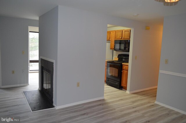 18050 Chalet Dr Unit 14-303, Germantown, MD 20874 - kitchen with black appliances, a glass covered fireplace, light wood finished floors, and brown cabinets