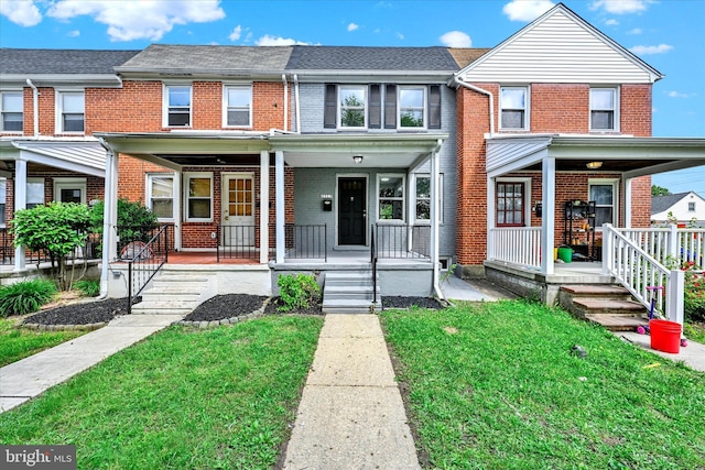 multi unit property featuring a porch, brick siding, and a front lawn