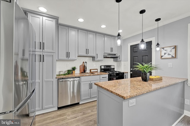kitchen with appliances with stainless steel finishes, a sink, under cabinet range hood, gray cabinets, and crown molding