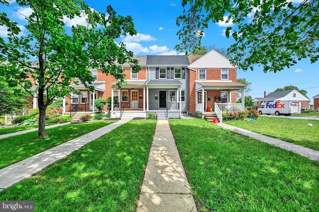 view of property with brick siding, covered porch, and a front yard