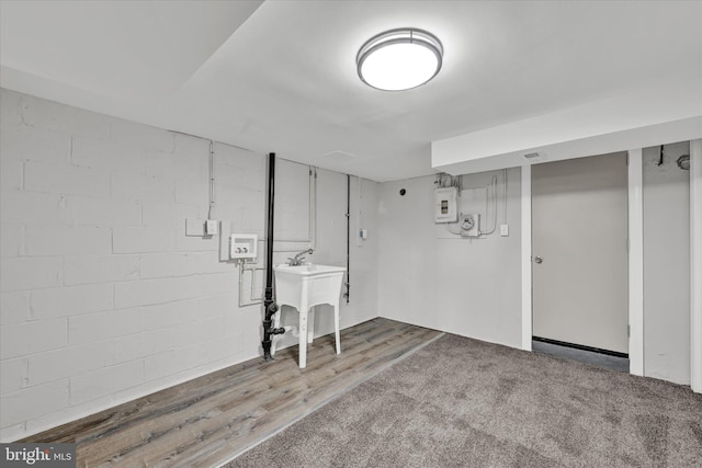 finished below grade area featuring a sink, wood finished floors, and electric panel