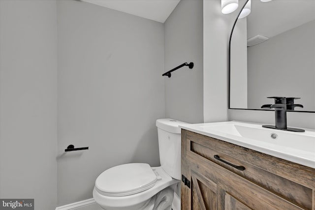 half bathroom with toilet, vanity, and baseboards