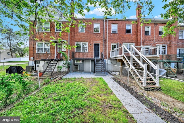 rear view of house featuring stairs, brick siding, and a fenced backyard