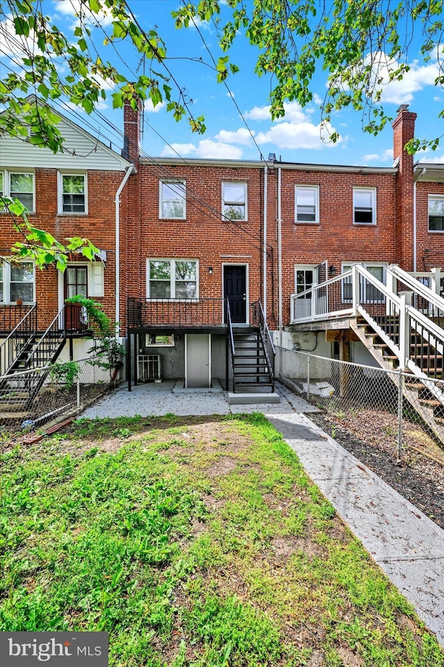 rear view of house with stairway and brick siding