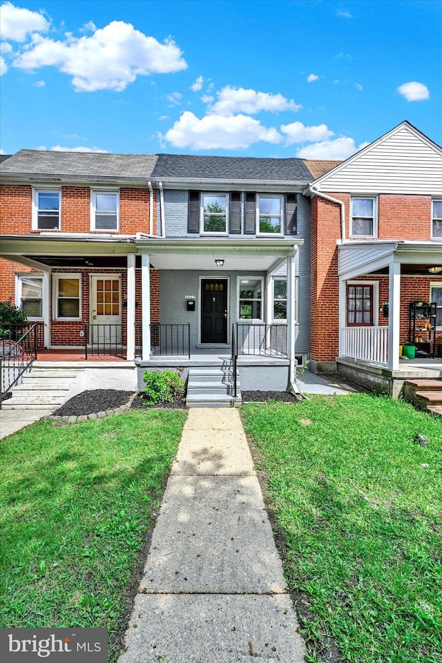 townhome / multi-family property featuring a porch, brick siding, and a front yard