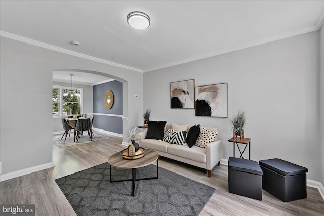 living area featuring arched walkways, ornamental molding, baseboards, and wood finished floors