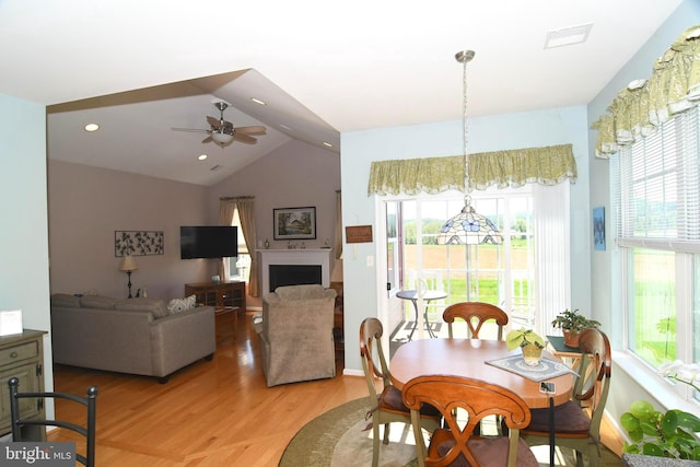 dining space featuring plenty of natural light, light wood-style floors, ceiling fan, lofted ceiling, and a fireplace