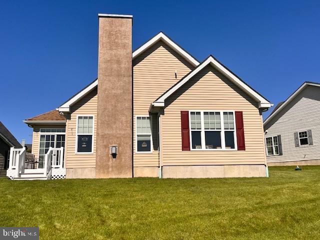 rear view of property featuring a yard and a chimney