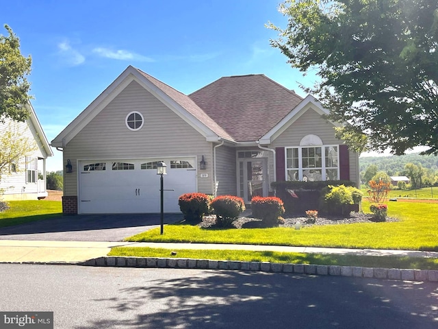 ranch-style house featuring asphalt driveway, a front yard, an attached garage, and roof with shingles
