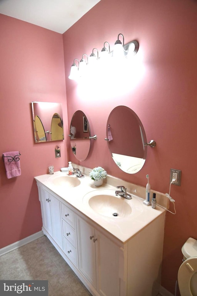 full bath featuring double vanity, toilet, tile patterned flooring, and baseboards