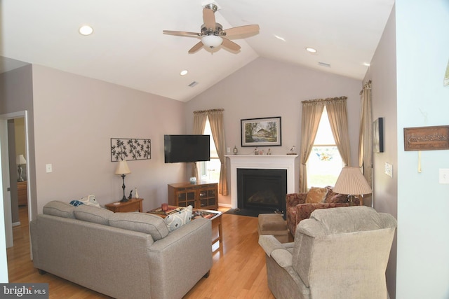 living area featuring a ceiling fan, vaulted ceiling, light wood-type flooring, a fireplace with flush hearth, and recessed lighting