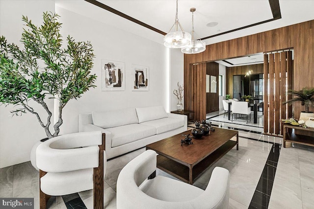 living area with wooden walls, a chandelier, and marble tiled floors