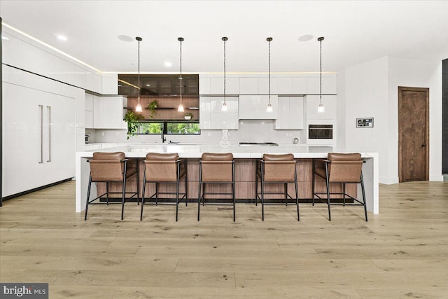 kitchen with modern cabinets, white cabinets, light wood finished floors, and light countertops