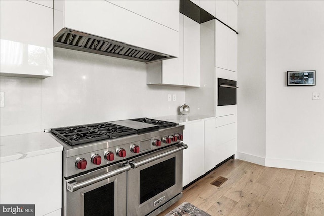 kitchen featuring range with two ovens, white cabinetry, light wood-style floors, and light countertops