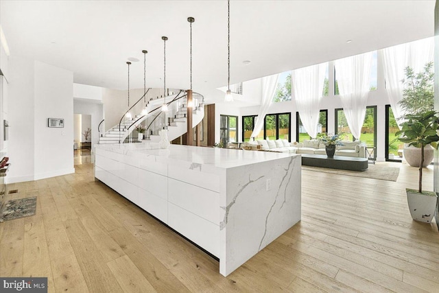 kitchen with modern cabinets, healthy amount of natural light, decorative light fixtures, and light wood-type flooring