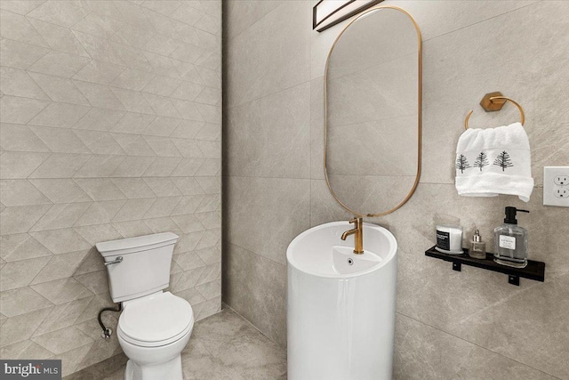 half bathroom featuring toilet and tile walls