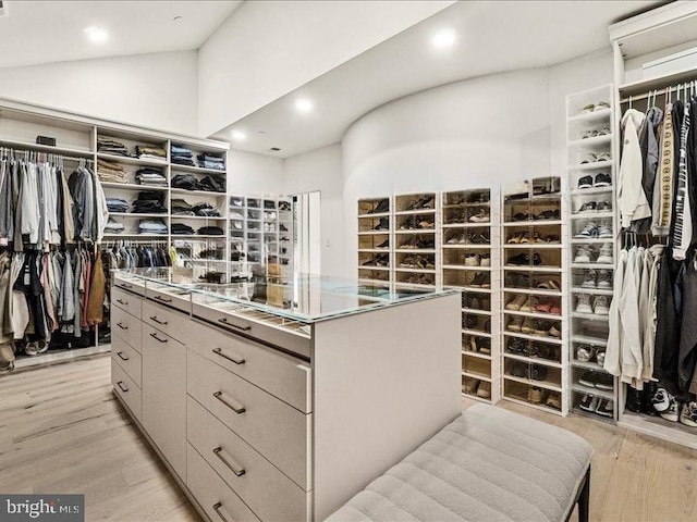 walk in closet with light wood-type flooring and lofted ceiling