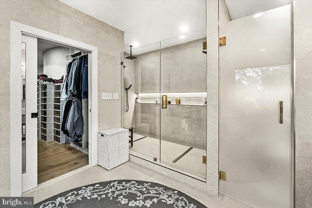 bathroom featuring a stall shower, a walk in closet, and recessed lighting