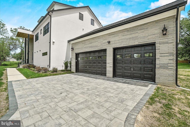 view of side of property featuring decorative driveway and an attached garage