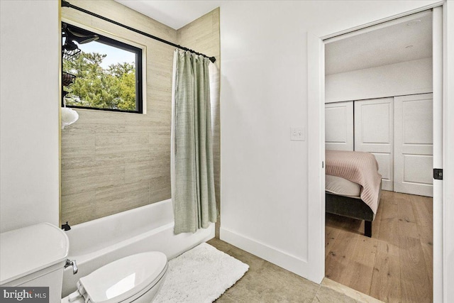 bathroom featuring toilet, shower / bath combination with curtain, and baseboards