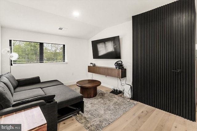 living area with vaulted ceiling, wood finished floors, and baseboards