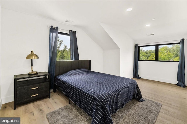 bedroom featuring multiple windows, light wood-type flooring, vaulted ceiling, baseboards, and recessed lighting