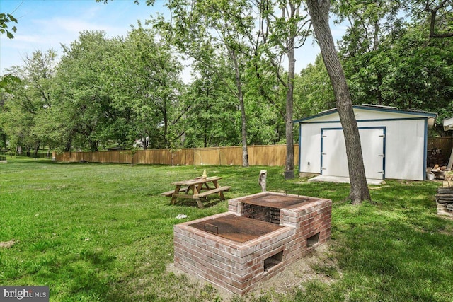 view of yard featuring a storage shed, an outdoor structure, and view of wooded area