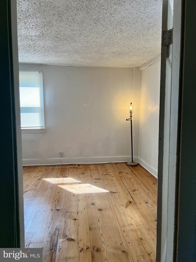 empty room featuring hardwood / wood-style flooring, baseboards, and a textured ceiling