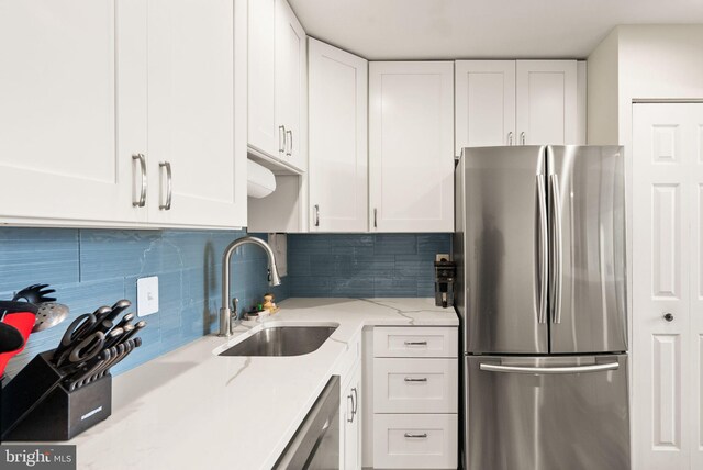 7 Canterbury Sq Unit 401, Alexandria, VA 22304 - kitchen featuring appliances with stainless steel finishes, a sink, white cabinetry, backsplash, and light stone countertops