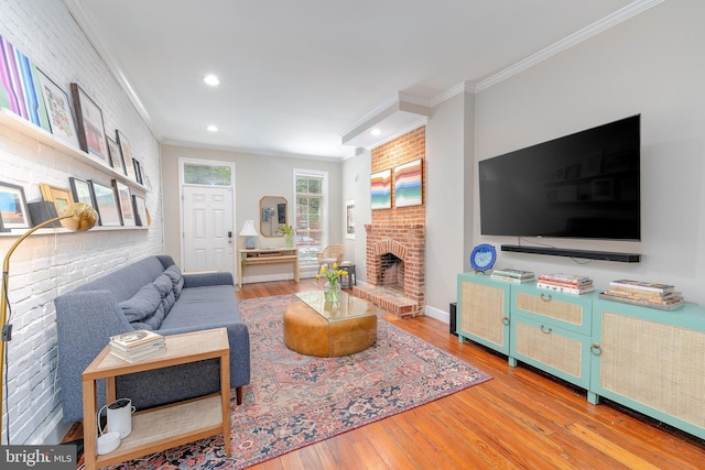 living area with ornamental molding, wood-type flooring, recessed lighting, a brick fireplace, and baseboards