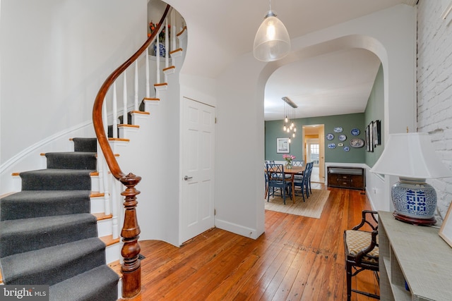 staircase featuring arched walkways and hardwood / wood-style floors
