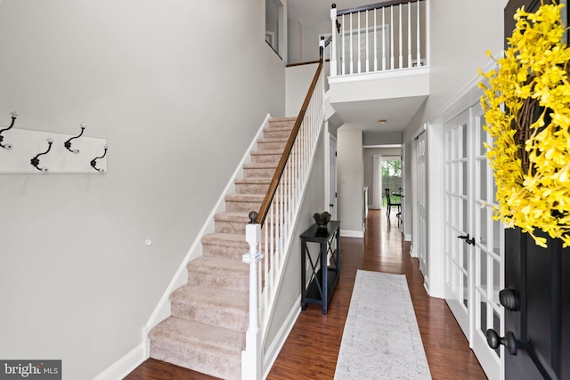 entryway with stairs, dark wood-style floors, baseboards, and a high ceiling