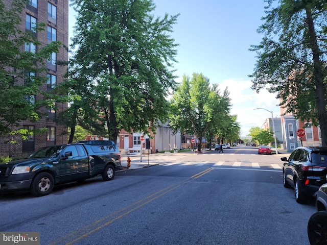 view of asphalt street featuring traffic signs, street lighting, sidewalks, and curbs