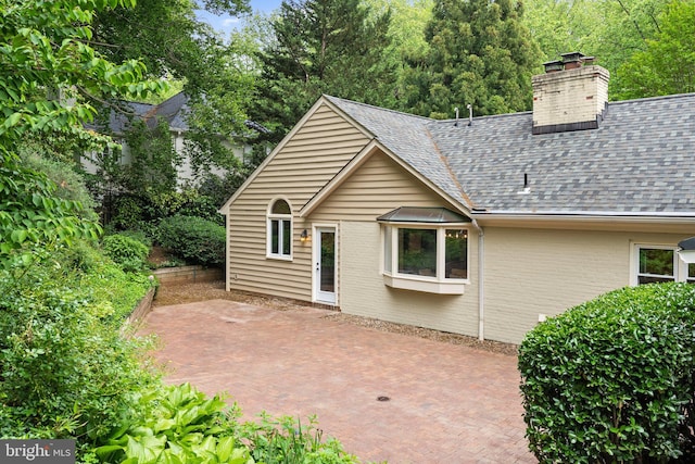 4009 30th St N, Arlington, VA 22207 - rear view of house with a patio area, roof with shingles, brick siding, and a chimney