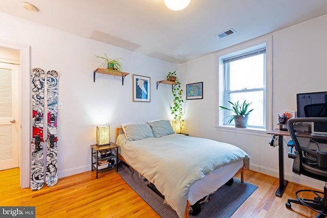 bedroom with light wood-type flooring, baseboards, and a desk