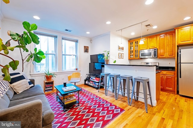 living room featuring light wood-type flooring, ornamental molding, and recessed lighting