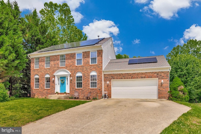 2452 Tuckahoe Ct, Waldorf, MD 20601 - georgian-style home with solar panels, a front lawn, brick siding, concrete driveway, and an attached garage