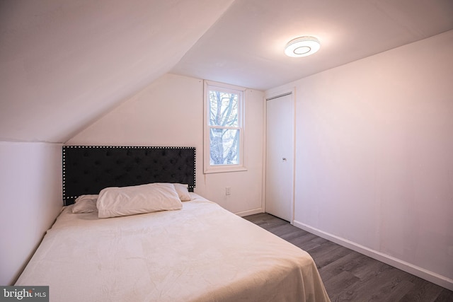 bedroom featuring wood finished floors, vaulted ceiling, and baseboards