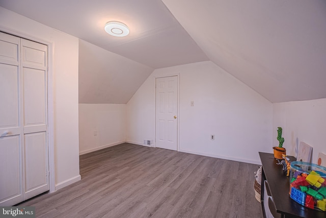 additional living space with wood finished floors, lofted ceiling, and baseboards
