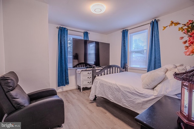 bedroom with wood finished floors and multiple windows